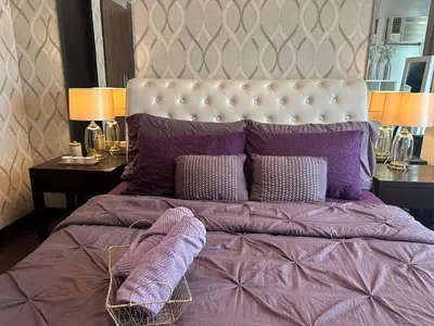 a bedroom with a large bed with purple sheets and pillows at Condo in BGC near Grand Hyatt Hotel in Manila