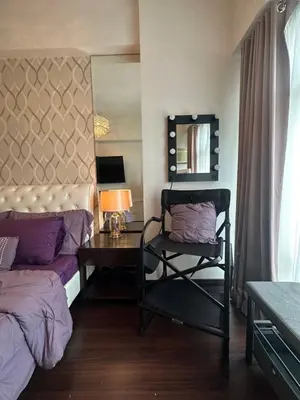 a bedroom with a bed and a table and a mirror at Condo in BGC near Grand Hyatt Hotel in Manila
