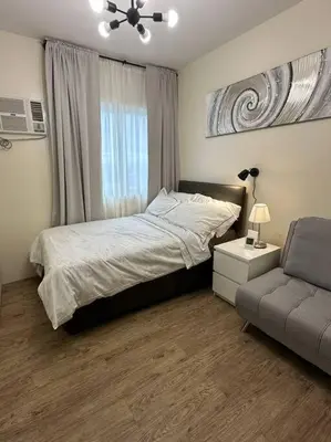 a bedroom with a bed and a chair and a window at Affordable Condo Near Nuvali in Silang