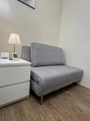 a gray couch sitting next to a desk with a lamp at Affordable Condo Near Nuvali in Silang