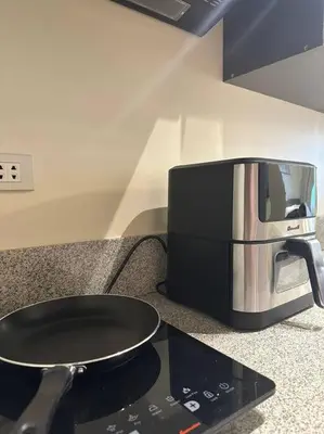 a microwave sitting on top of a stove with a pan at Affordable Condo Near Nuvali in Silang
