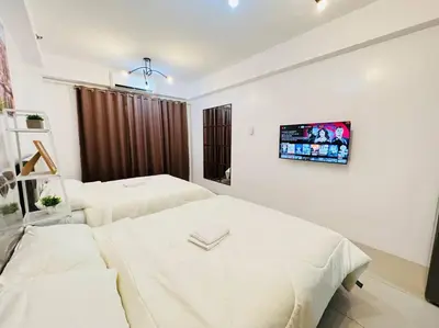 a room with two beds and a tv on the wall at Katrina Suite infront of Mall of Asia and Bay area in Manila