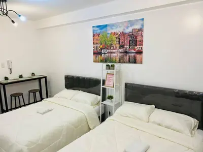 two beds in a room with a painting on the wall at Katrina Suite infront of Mall of Asia and Bay area in Manila