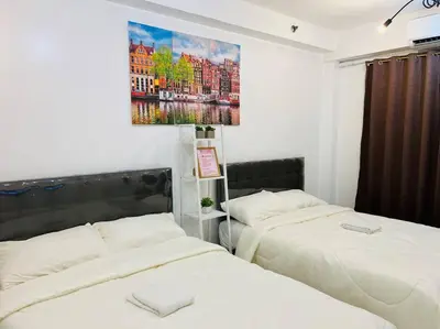 a bedroom with two beds and a painting on the wall at Katrina Suite infront of Mall of Asia and Bay area in Manila