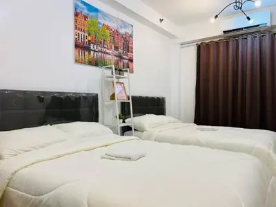 three beds in a room with white sheets at Katrina Suite infront of Mall of Asia and Bay area in Manila