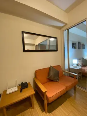 a living room with an orange couch and a mirror at Positano 1br Beach View in Manila