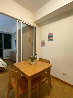 a wooden table and chairs in a room at Positano 1br Beach View in Manila