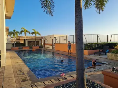 a woman standing next to a swimming pool with a palm tree at Cute Studio Unit w/ Big Windows - B Morgan T1 in Manila