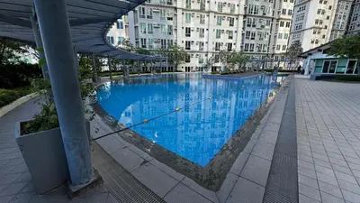a large blue swimming pool with a building in the background at Toby’s Crib at San Lorenzo Place in Manila