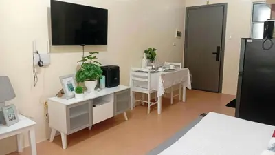 a living room with a table and a tv on the wall at Coho The Hermosa - Staycation Studio Unit and Balcony View with Swimming Pool and Open Court access in Manila