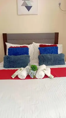 a bed with red and blue pillows and flowers on it at Coho The Hermosa - Staycation Studio Unit and Balcony View with Swimming Pool and Open Court access in Manila