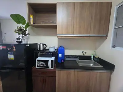 a small kitchen with a sink and a black refrigerator at Coho The Hermosa - Staycation Studio Unit and Balcony View with Swimming Pool and Open Court access in Manila