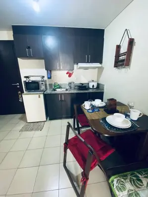 a kitchen with a table and a kitchen with black cabinets at Condo in Metro Manila V PAD in Manila