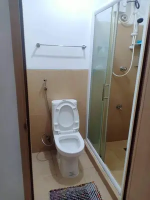 a small bathroom with a toilet and a shower at Humble Abode de Gloria in Manila