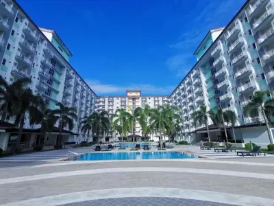 a large apartment building with a swimming pool and palm trees at Humble Abode de Gloria in Manila