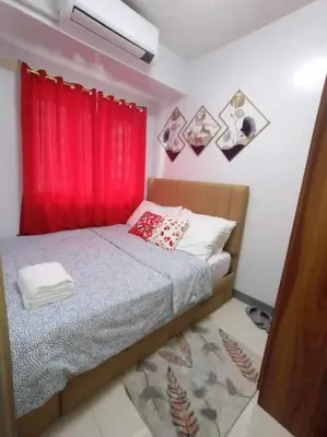 a bedroom with a bed with a red curtain at Staycation Near MOA by Cozypura with Pay Parking at S Res MOA in Manila