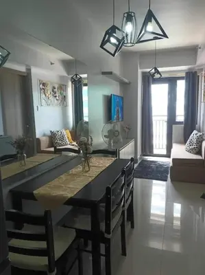 a dining room and living room with a table and chairs at Staycation Near MOA by Cozypura with Pay Parking at S Res MOA in Manila