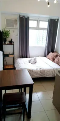 a bedroom with a bed and a table and a window at Urban Deca Tower Edsa Mandaluyong Staycation Condotel in Manila