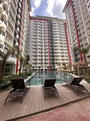 a large building with a swimming pool and two chairs at Paranaque Manila Bloom residences in Manila