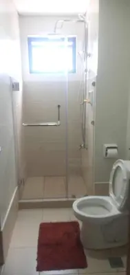 a bathroom with a shower and a toilet with a red rug at Paranaque Manila Bloom residences in Manila