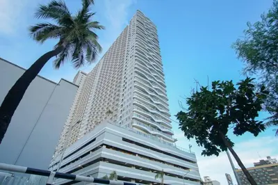 a tall white building with a palm tree in front of it at CitiBay View Staycation in Manila