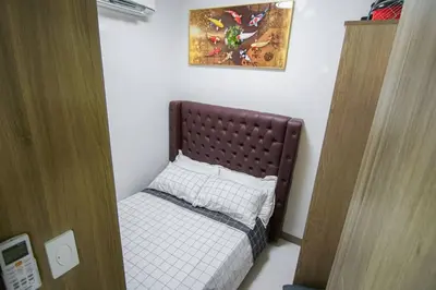 a small bedroom with a bed with a brown headboard at CitiBay View Staycation in Manila