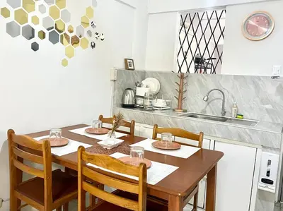 a kitchen with a wooden table with chairs and a sink at Suite Dreams Staycation - Cozy 2-BR - Wi-Fi Garden Kitchen in Dasmariñas
