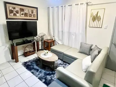 a living room with a couch and a tv at Suite Dreams Staycation - Cozy 2-BR - Wi-Fi Garden Kitchen in Dasmariñas