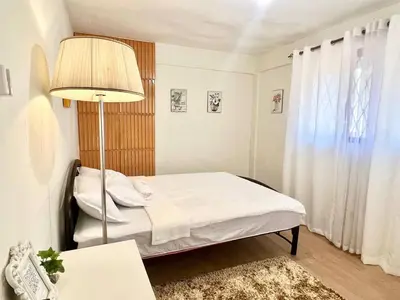 a small bedroom with a bed and a lamp at Suite Dreams Staycation - Cozy 2-BR - Wi-Fi Garden Kitchen in Dasmariñas