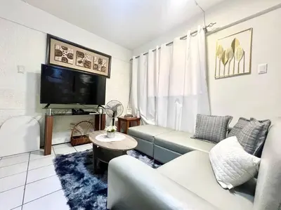 a living room with a couch and a tv at Suite Dreams Staycation - Cozy 2-BR - Wi-Fi Garden Kitchen in Dasmariñas
