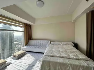 a bedroom with a bed and a large window at 2 Bedroom Loft at Twin Oaks Place in Manila