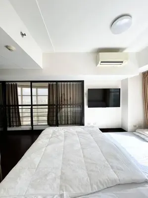 a large white bed in a room with windows at 2 Bedroom Loft at Twin Oaks Place in Manila