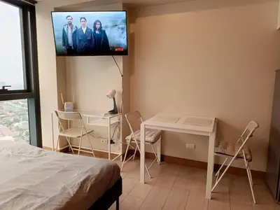 a room with a table and a tv on the wall at Eastwood Staycation Home with Stunning City View minimum 2nights stay in Manila