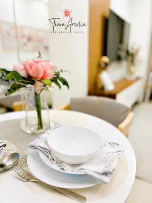 a table with a bowl and plates and a vase of flowers at Condo near MOA Pasay and NAIA Manila Airport in Manila