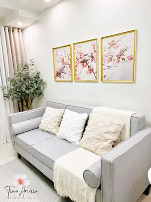 a gray couch in a living room with three paintings on the wall at Condo near MOA Pasay and NAIA Manila Airport in Manila