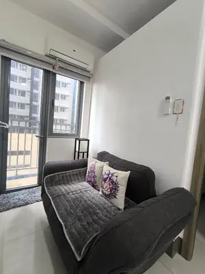 a couch in a living room with a large window at Fame Residence 701 Tower 2 in Manila