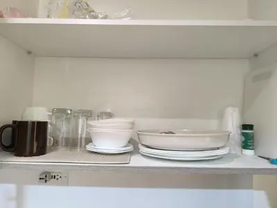 a shelf with white bowls and plates on it at Fame Residence 701 Tower 2 in Manila