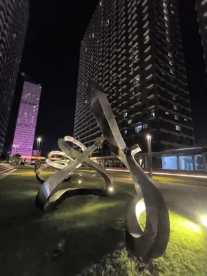 a large metal sculpture in a city at night at Fame Residence 701 Tower 2 in Manila