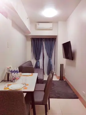 a living room with a table and a couch and a television at Condo near Mall of Asia in Manila
