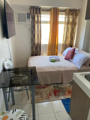 a bedroom with a bed and a desk and a window at Pierrecondotel in Manila