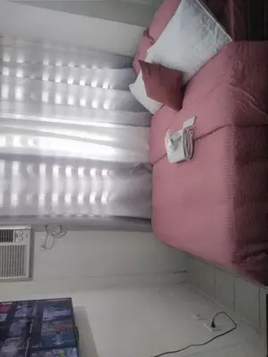 a bed with pink sheets and pillows next to a window at Pierrecondotel in Manila