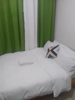 a bed with white sheets and a green curtain at Pierrecondotel in Manila