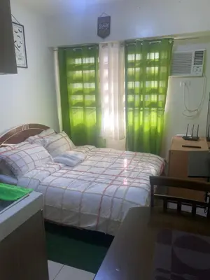 a bedroom with a bed with green curtains and a desk at Pierrecondotel in Manila