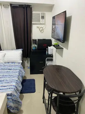 a small room with a table and a desk with a television at pierrecondotel in Manila