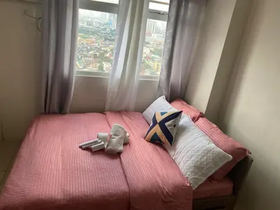 a small bed with a teddy bear and a window at pierrecondotel in Manila