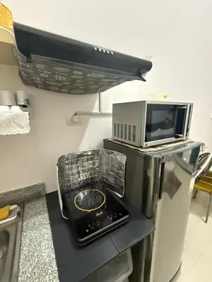 a microwave sitting on top of a counter next to a table at Simple Yet Special n SOUTH RESIDENCES in Manila