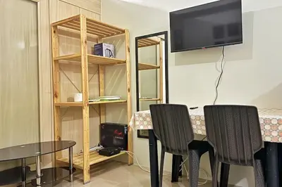 a room with a table and two chairs and a tv at Meowcation Condo in Makati in Manila