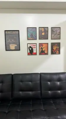 a black leather couch against a white wall with pictures at Meowcation Condo in Makati in Manila