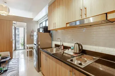 a kitchen with a sink and a refrigerator at ClaySky Staycation S2T1-Cozy & Homey 1BR Apartment near MOA facing Pool with Own Parking with Netflix, HBO Max YouTube Premium & up to 200mbps Wifi in Manila