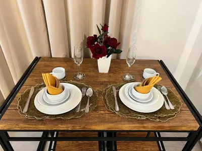 a table with plates and glasses and a vase of flowers at Comfty, Chic & Spacious Room with Parking & WiFi in Manila